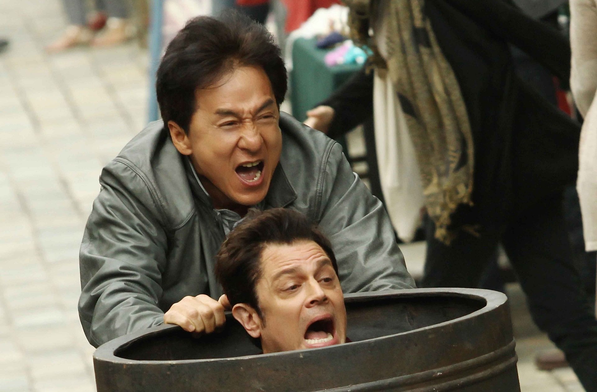Jackie Chan and Renny Harlin in a comedic scene from the movie *Skiptrace* (2016), showcasing their dynamic as they navigate a humorous chase. HD desktop wallpaper.
