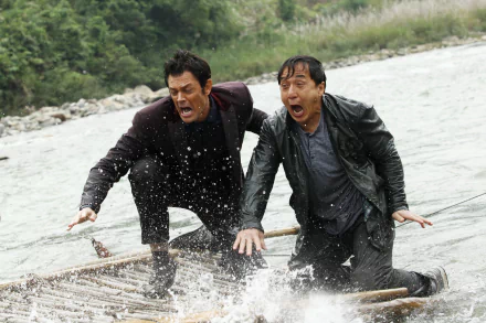 Jackie Chan and a companion face a thrilling moment on a raft in a river, capturing an action-packed scene from the movie Skiptrace (2016), directed by Renny Harlin.