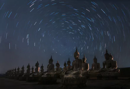 A stunning time-lapse scene of a starry night sky above seated Buddha statues in Thailand, capturing the serene beauty of the religious landscape in HD resolution.