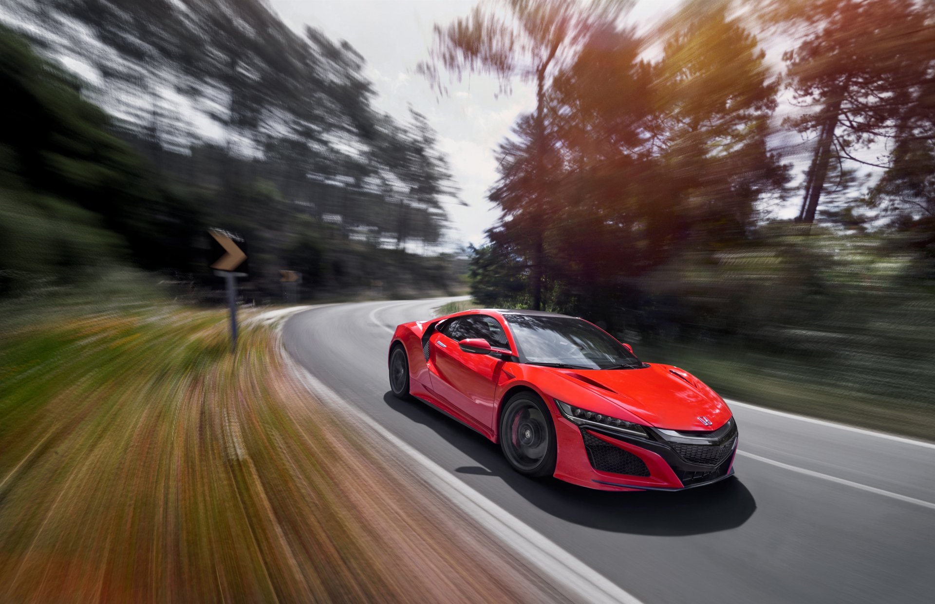 A vibrant red Honda NSX supercar speeds along a winding road with motion blur, captured in stunning 4K Ultra HD as a dynamic PC desktop wallpaper.
