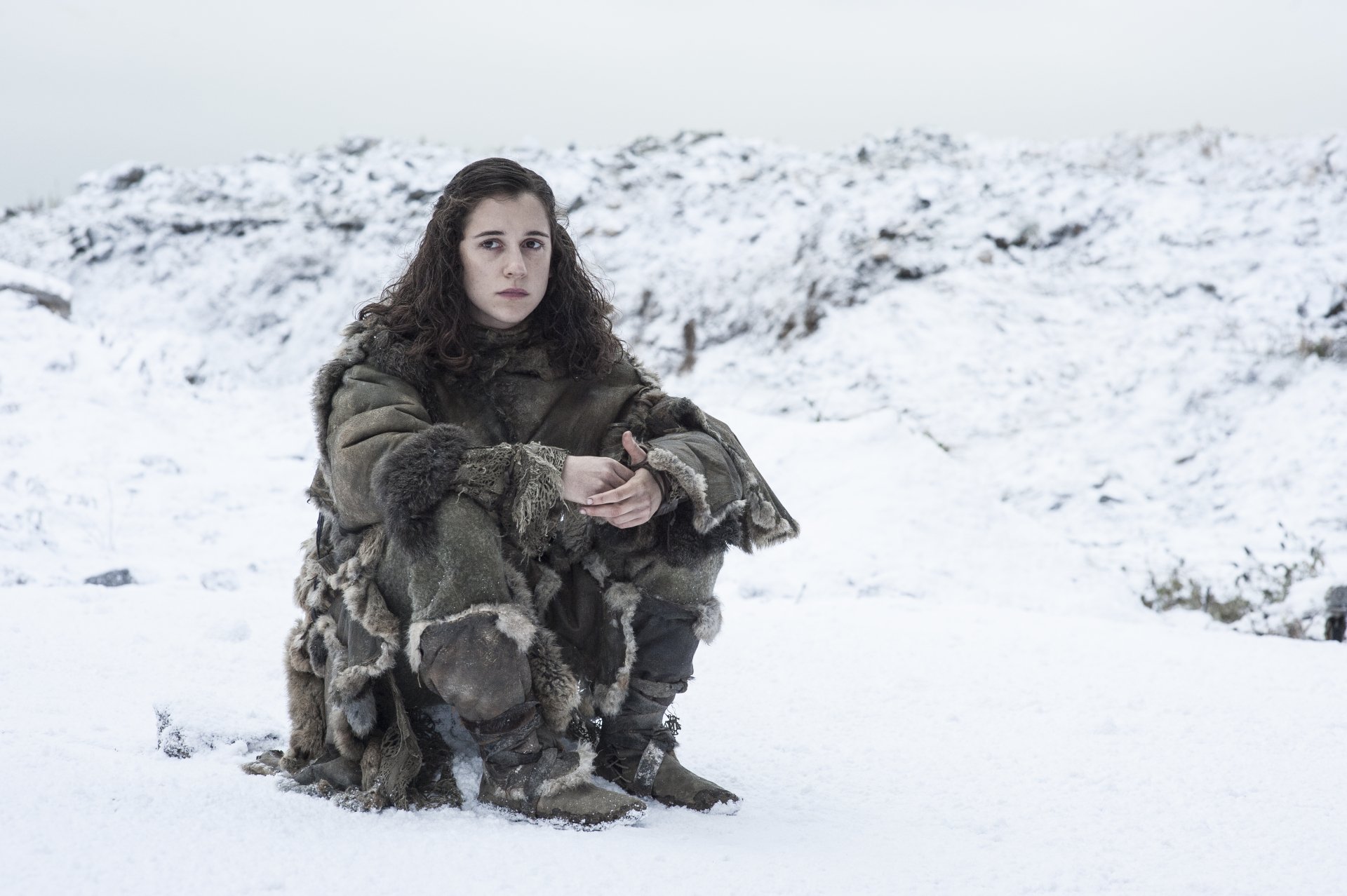 Crouching young woman in a heavy fur cloak on a snowy plain — Game of Thrones TV show 4K Ultra HD PC desktop wallpaper.