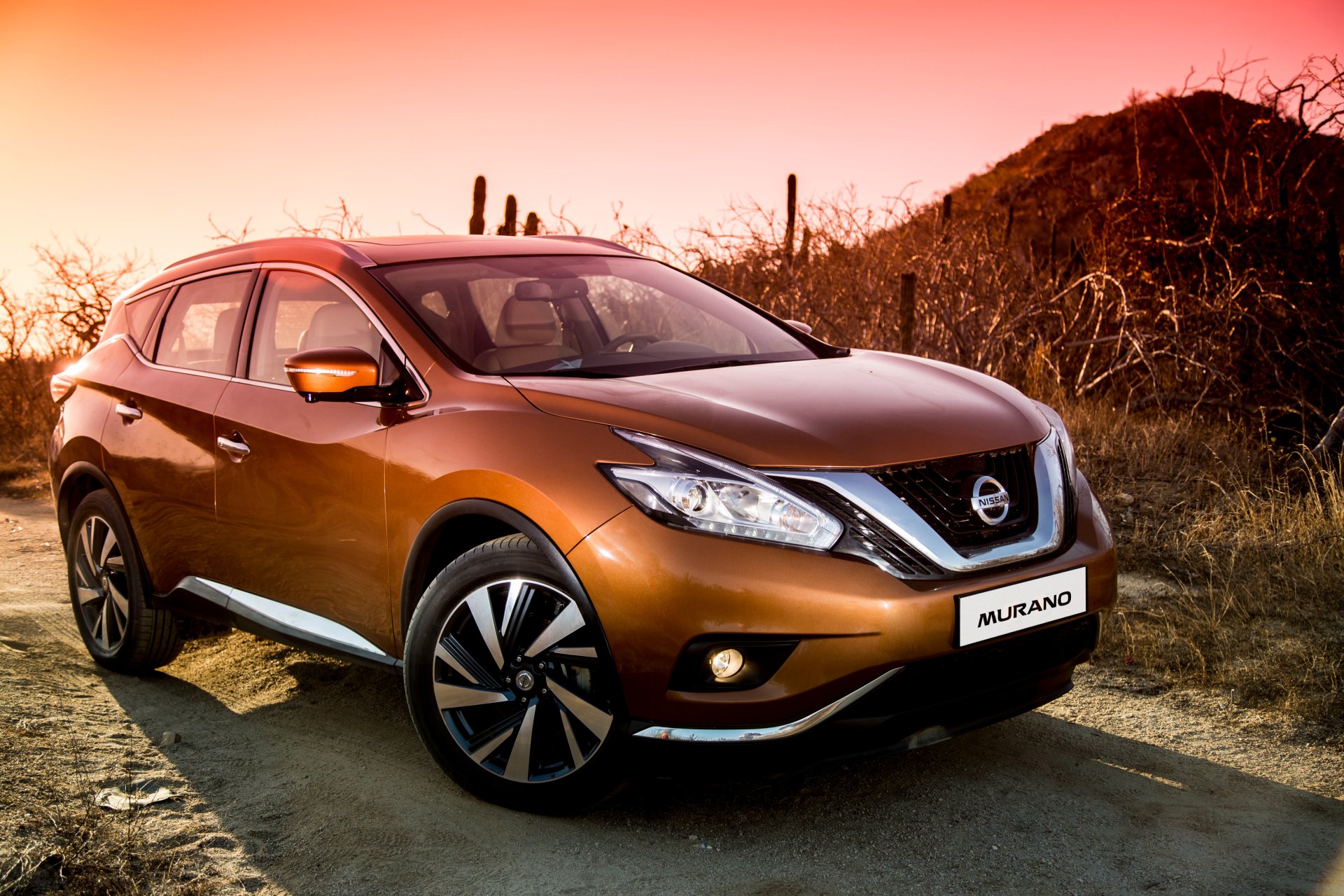 Orange Nissan Murano SUV car parked on a desert road at sunset, vivid 4K Ultra HD PC desktop wallpaper background.