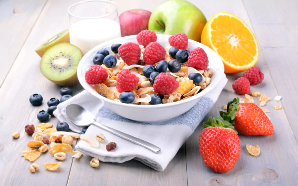A vibrant 8K Ultra HD desktop wallpaper featuring a bowl of muesli topped with raspberries, blueberries, and strawberries, surrounded by apple, kiwi, orange, and milk.