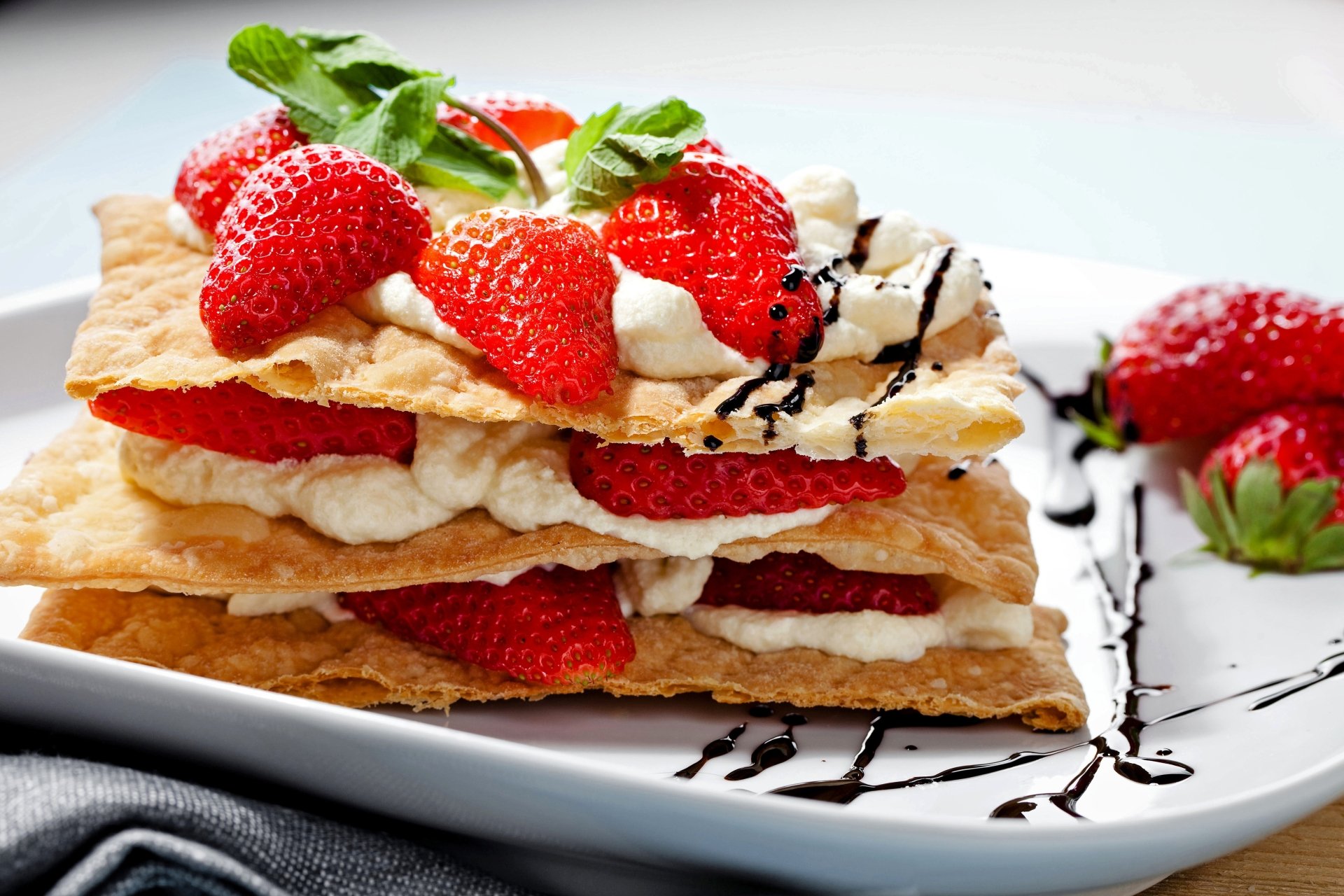 A 4K Ultra HD desktop wallpaper featuring a layered dessert of fresh strawberries and cream between crispy pastry, garnished with mint and drizzled chocolate.