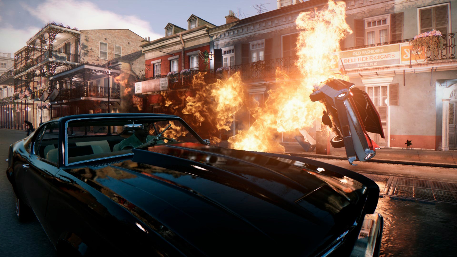 4K Ultra HD Mafia III PC wallpaper showing a vintage car in the foreground with a fiery explosion and a flipping vehicle on a city street in the background.