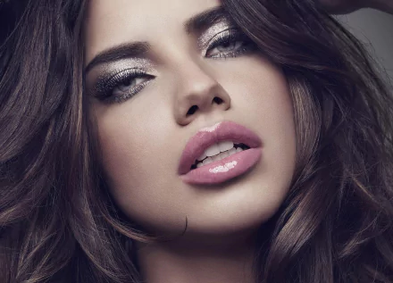 Close-up HD desktop wallpaper of celebrity Adriana Lima with glossy lips and smoky eye makeup, highlighting her striking features against a dark background.