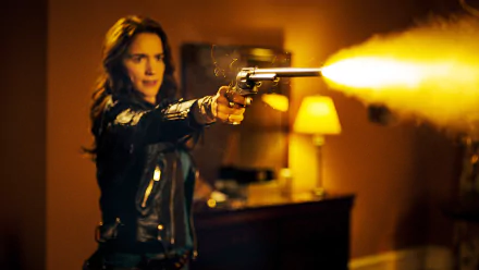Melanie Scrofano as Wynonna Earp firing a gun in a dramatic scene from the TV show, captured in HD for a PC desktop wallpaper.