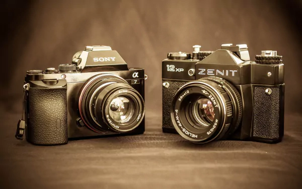 HD desktop wallpaper showing two man-made cameras — a Sony mirrorless with lens beside a vintage Zenit SLR on a warm sepia background.