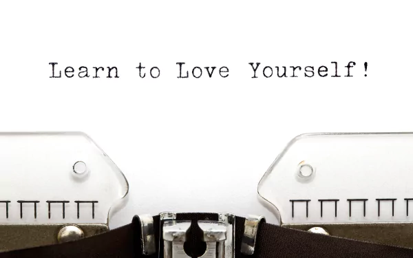 A motivational 4K Ultra HD wallpaper featuring a vintage typewriter with the message Learn to Love Yourself! encourages self-acceptance and positivity.