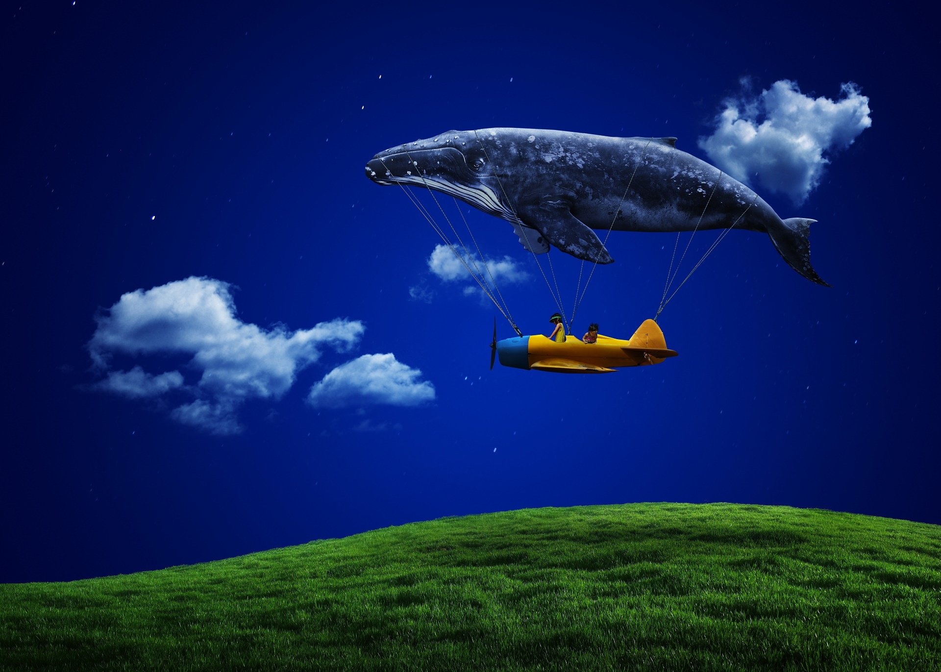 Artistic dreamscape HD desktop wallpaper depicting a giant whale tethered to a small yellow airplane flying over a green hill beneath a deep blue sky with scattered clouds.