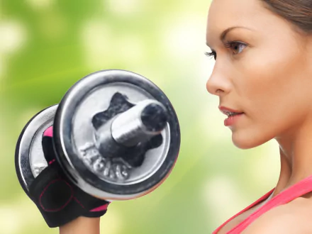Close-up face of a woman with brown eyes lifting a dumbbell during a sports weightlifting workout — 4K Ultra HD PC desktop wallpaper background.