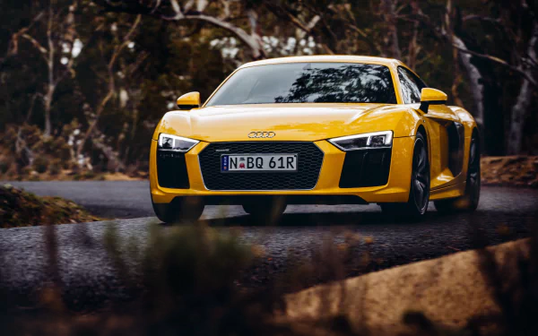Yellow Audi R8 V10 supercar driving on a winding road, captured in sharp 4K Ultra HD quality for a dynamic PC desktop wallpaper background.