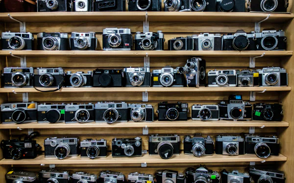 HD desktop wallpaper featuring a collection of vintage man-made cameras neatly arranged on wooden shelves.