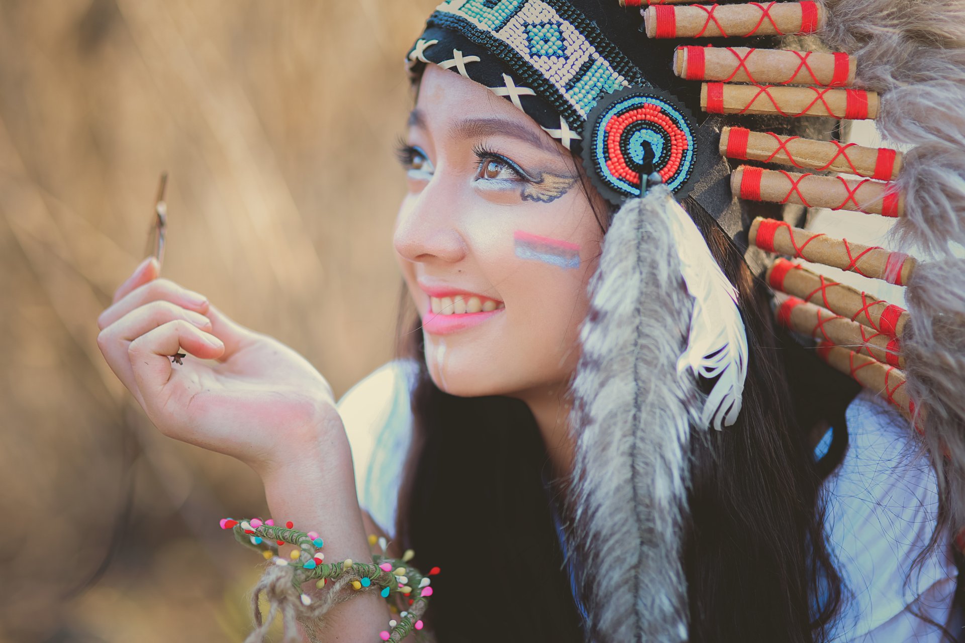 A Native American woman wearing a traditional feathered headdress and face paint, captured in a vibrant 4K Ultra HD desktop wallpaper.