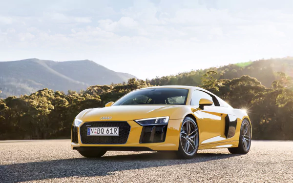 Yellow Audi R8 V10 supercar parked on a scenic road with mountains and trees in the background, displayed in 4K Ultra HD quality for desktop wallpaper.