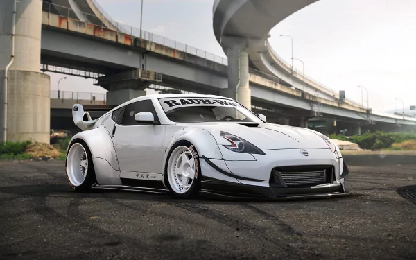 White Nissan 370Z with wide body kit and custom rims parked under an urban overpass, showcased as a high-definition PC desktop wallpaper background.
