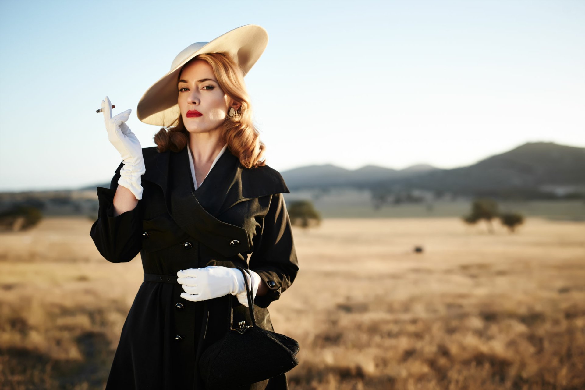 HD desktop wallpaper featuring blonde English actress Kate Winslet in a fashion hat and lipstick, portraying her role in the movie The Dressmaker.