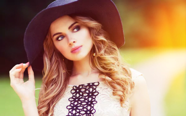 A brunette woman with blue eyes and a hat enjoys a sunny day outdoors in this HD desktop wallpaper background.
