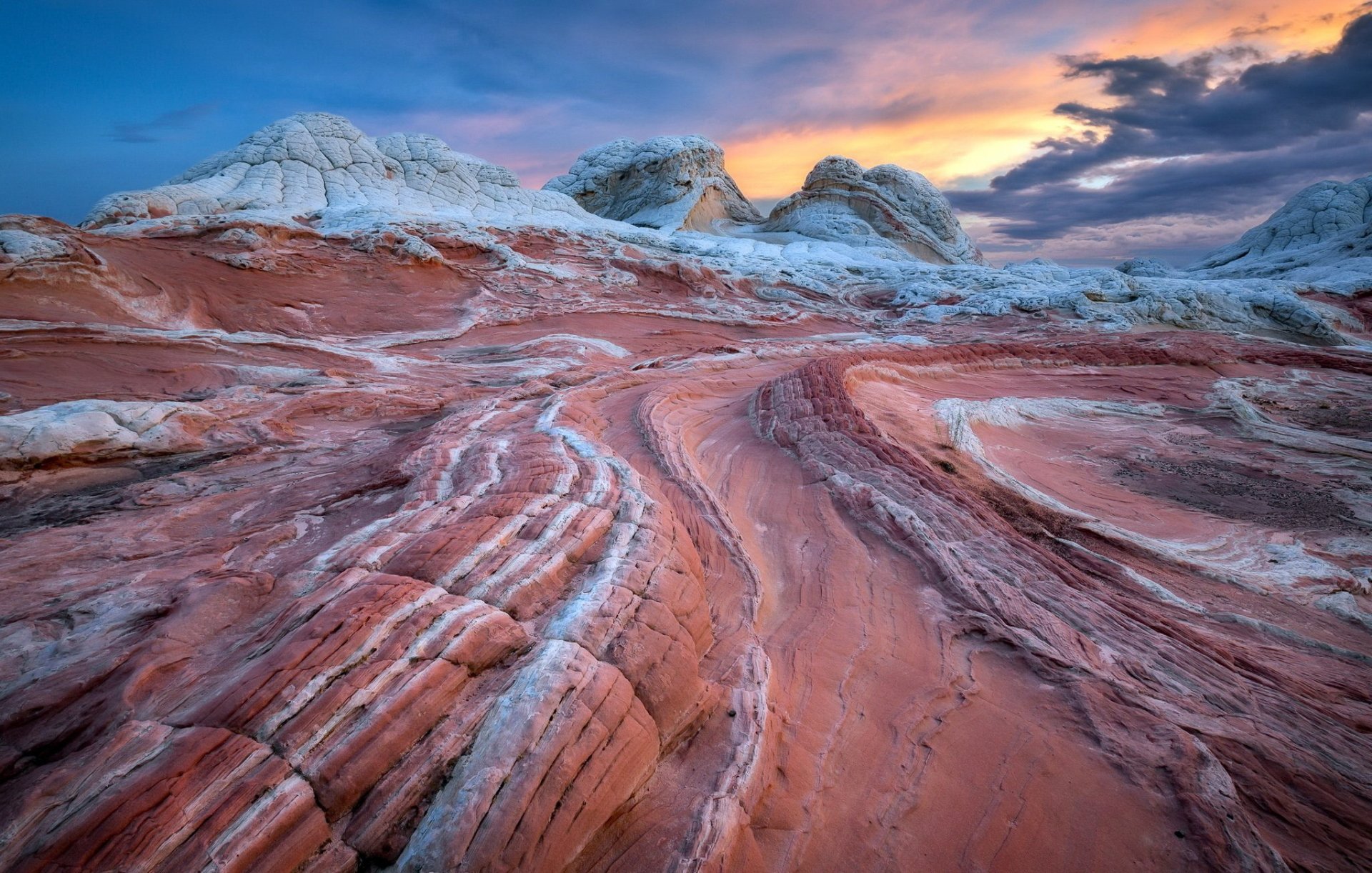 HD desktop wallpaper showcasing a vibrant natural rock formation with layered red and white patterns under a colorful sunset sky.