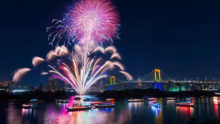 Night view of Tokyo's Rainbow Bridge in Japan illuminated with colorful lights and fireworks over Tokyo Bay, reflected on water — HD desktop wallpaper photography of bridge, city and boats.
