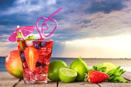A vibrant summer cocktail with strawberries, lime, and blueberries in a glass with a pink straw and umbrella, set against a dramatic cloudy sky and waterfront background in 4K Ultra HD.