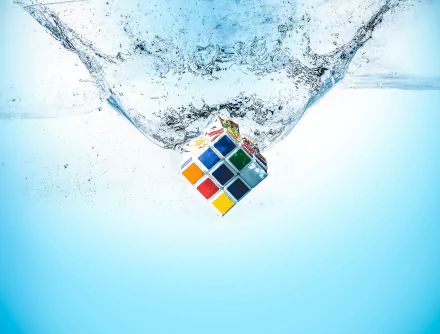 HD desktop wallpaper of a Rubik's cube splashing into water, capturing a dynamic moment with crystal-clear detail against a light blue background.