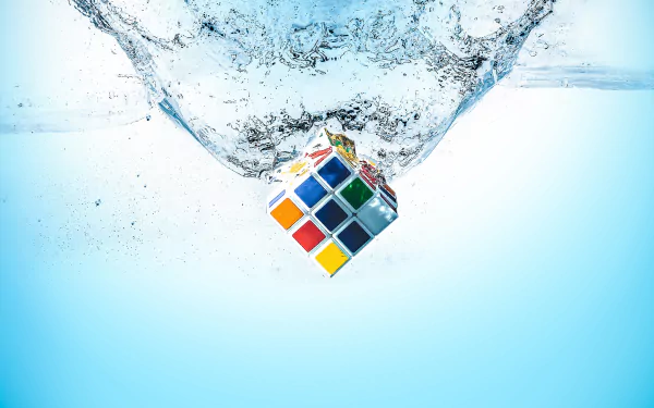 HD desktop wallpaper of a Rubik's cube splashing into water, capturing a dynamic moment with crystal-clear detail against a light blue background.