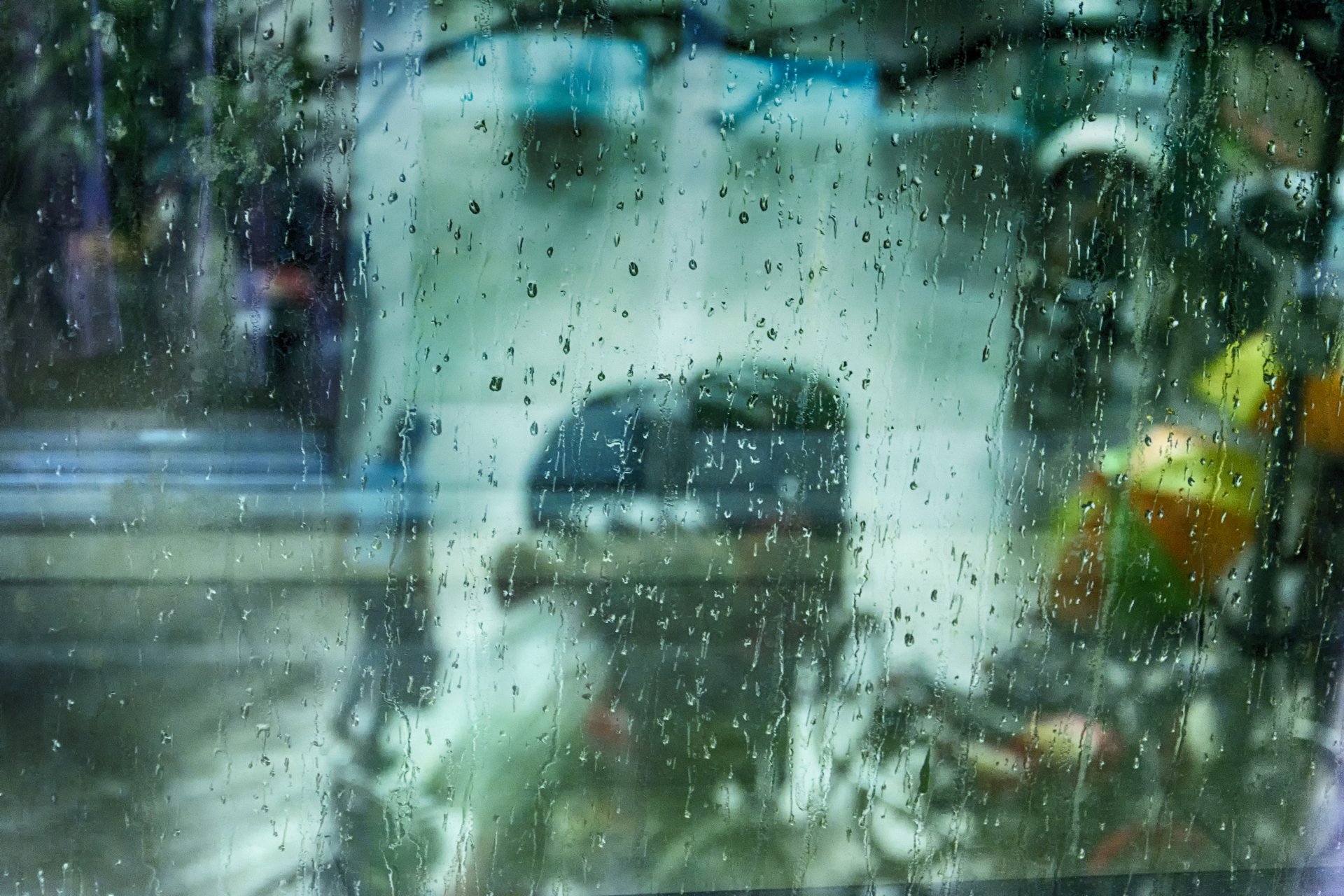 A close-up of water droplets on a window, capturing the essence of rain and its reflection on a bustling street. This high-definition image serves as a captivating desktop wallpaper.