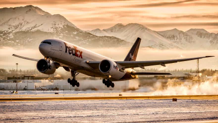 HD desktop wallpaper featuring a FedEx aircraft taking off, set against snow-covered mountains and a golden sky, highlighting the vehicle in dynamic motion.