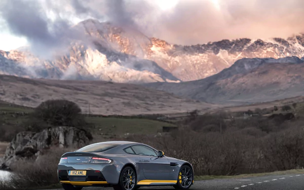 A sleek Aston Martin vehicle parked on a road with dramatic mountain peaks in the background, captured in stunning 4K Ultra HD for a PC desktop wallpaper.