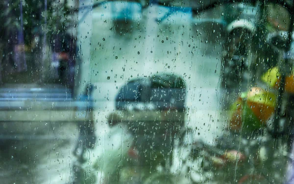 A close-up of water droplets on a window, capturing the essence of rain and its reflection on a bustling street. This high-definition image serves as a captivating desktop wallpaper.