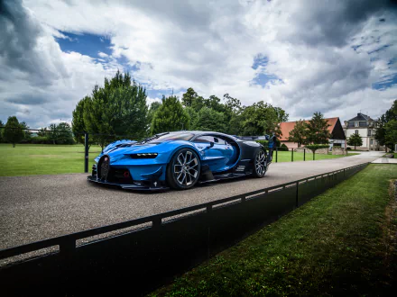 Blue Bugatti Chiron GT supercar on a paved road, set against a scenic backdrop with trees and a building under a dramatic cloudy sky. HD desktop wallpaper with vivid details.