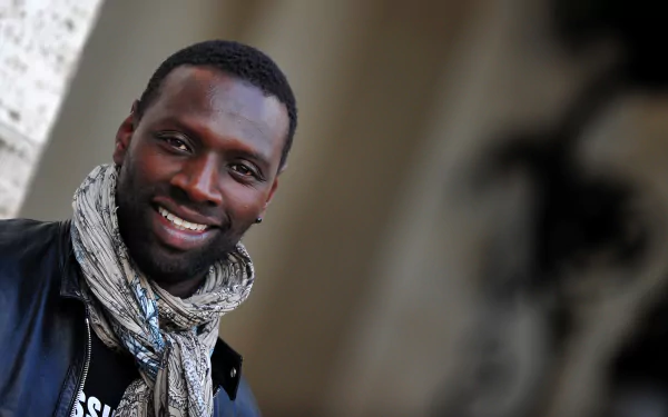Smiling man in a patterned scarf, portrait-style 2K Quad HD desktop wallpaper with a soft, blurred background.