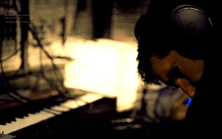 HD PC desktop wallpaper featuring a moody close-up of a musician wearing headphones beside a keyboard, inspired by Nine Inch Nails' music aesthetic.
