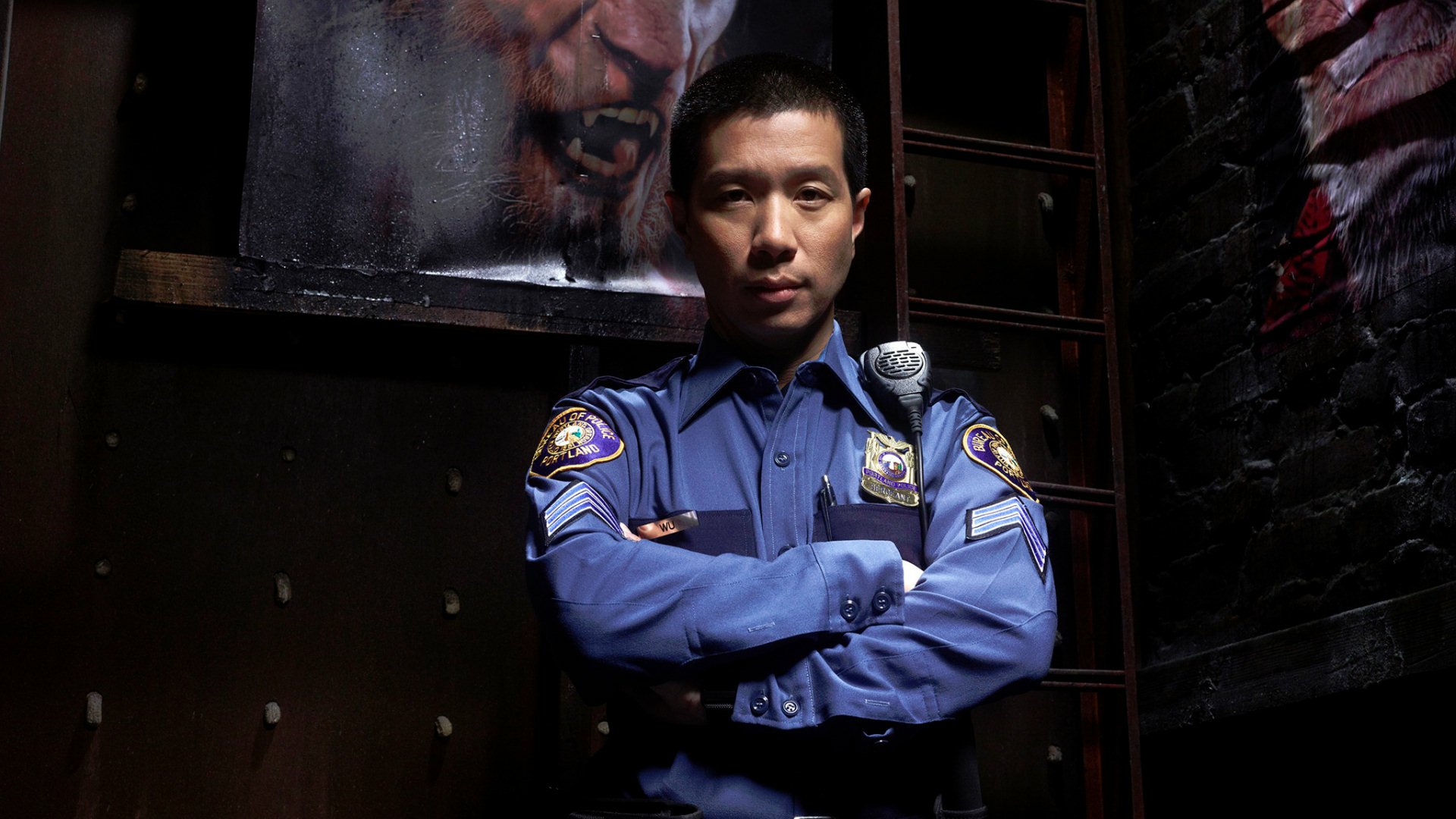 A character from the TV show Grimm poses confidently in a dark setting, wearing a police uniform and showcasing a serious demeanor, set against a backdrop of gritty artwork.