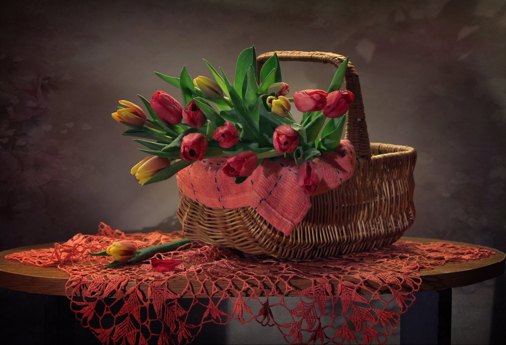 Still-life photography of yellow and pink tulips in a woven picnic basket on a lace cloth — 2K Quad HD PC desktop wallpaper/background.