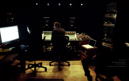 HD desktop wallpaper showing a dimly lit music studio with two people working at mixing consoles, associated with Nine Inch Nails.