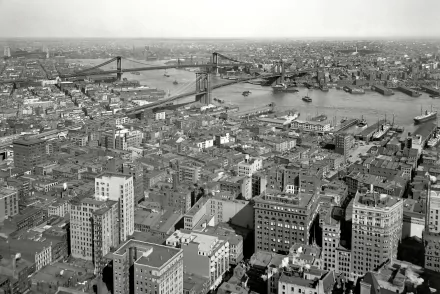 Black and white HD cityscape of New York, showing a river, bridges, and numerous buildings stretching to the horizon in this man-made urban environment.
