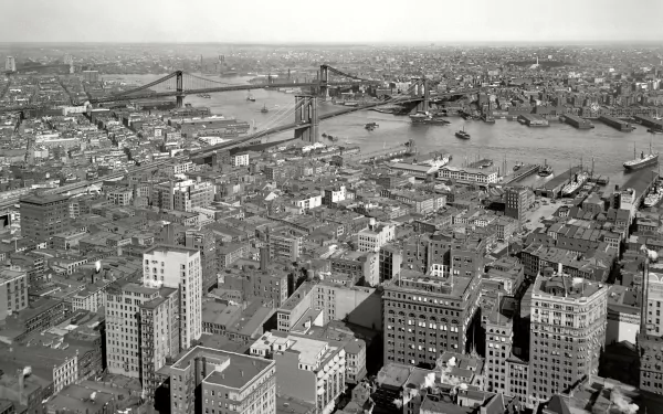 Black and white HD cityscape of New York, showing a river, bridges, and numerous buildings stretching to the horizon in this man-made urban environment.