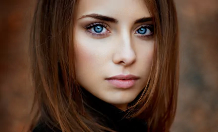 Close-up of a brunette woman with striking blue eyes, showcasing her delicate features and soft expression. An engaging HD desktop wallpaper and background image.