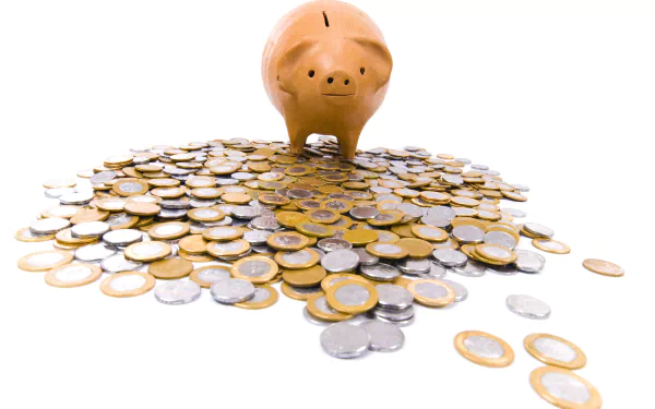 A man-made piggy bank stands atop a pile of mixed gold and silver coins, captured in a 4K Ultra HD desktop wallpaper background.