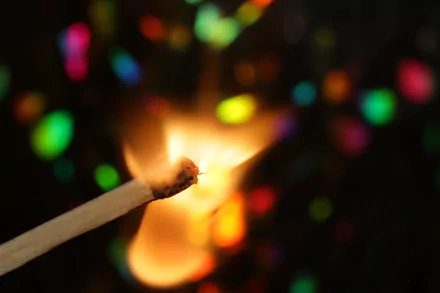 Close-up photograph of a burning match with warm flame and colorful bokeh, vibrant colors and soft-focus photography — 5K Ultra HD PC desktop wallpaper and background