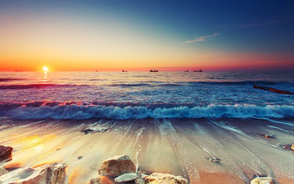 A serene beach at sunset, with gentle waves lapping the shore and a vibrant horizon, creating a stunning seascape that captures the beauty of nature. An ideal HD desktop wallpaper.