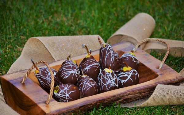 4K Ultra HD PC desktop wallpaper of chocolate-covered pears drizzled with white chocolate on a wooden tray — sweets, food still life background.