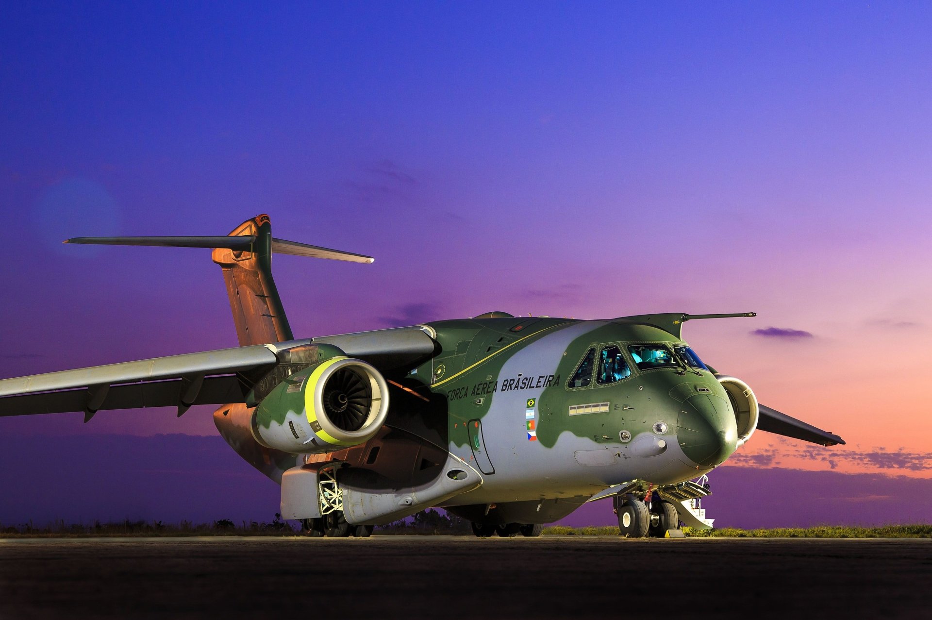 A striking Embraer KC-390 transport aircraft sits on the tarmac, showcasing its sleek design against a vibrant sunset, embodying modern military aviation.