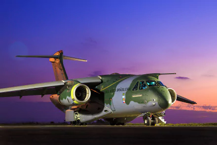 A striking Embraer KC-390 transport aircraft sits on the tarmac, showcasing its sleek design against a vibrant sunset, embodying modern military aviation.