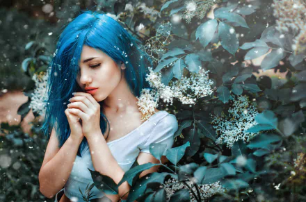 A woman with vibrant blue hair stands outdoors among lush leaves and white flowers, her contemplative mood captured in this HD desktop wallpaper.