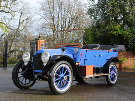 HD PC desktop wallpaper of a blue 1916 Packard Twin Six Touring vintage vehicle parked by an ornate gate and trees.