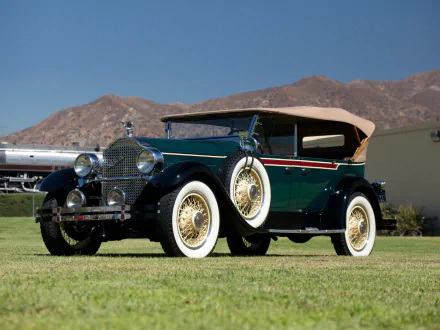 HD PC desktop wallpaper of a dark green 1927 Packard Six Phaeton vintage vehicle with whitewall tires parked on grass against a mountain backdrop.