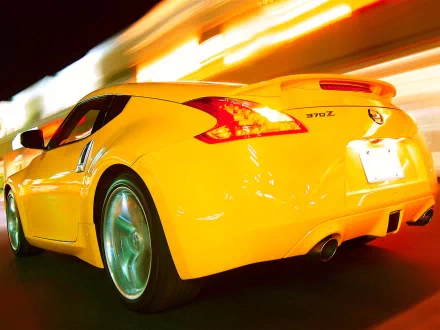 A vibrant yellow Nissan 370Z displayed in motion against a dynamic, colorful backdrop, creating an energetic and striking HD wallpaper for desktop backgrounds.